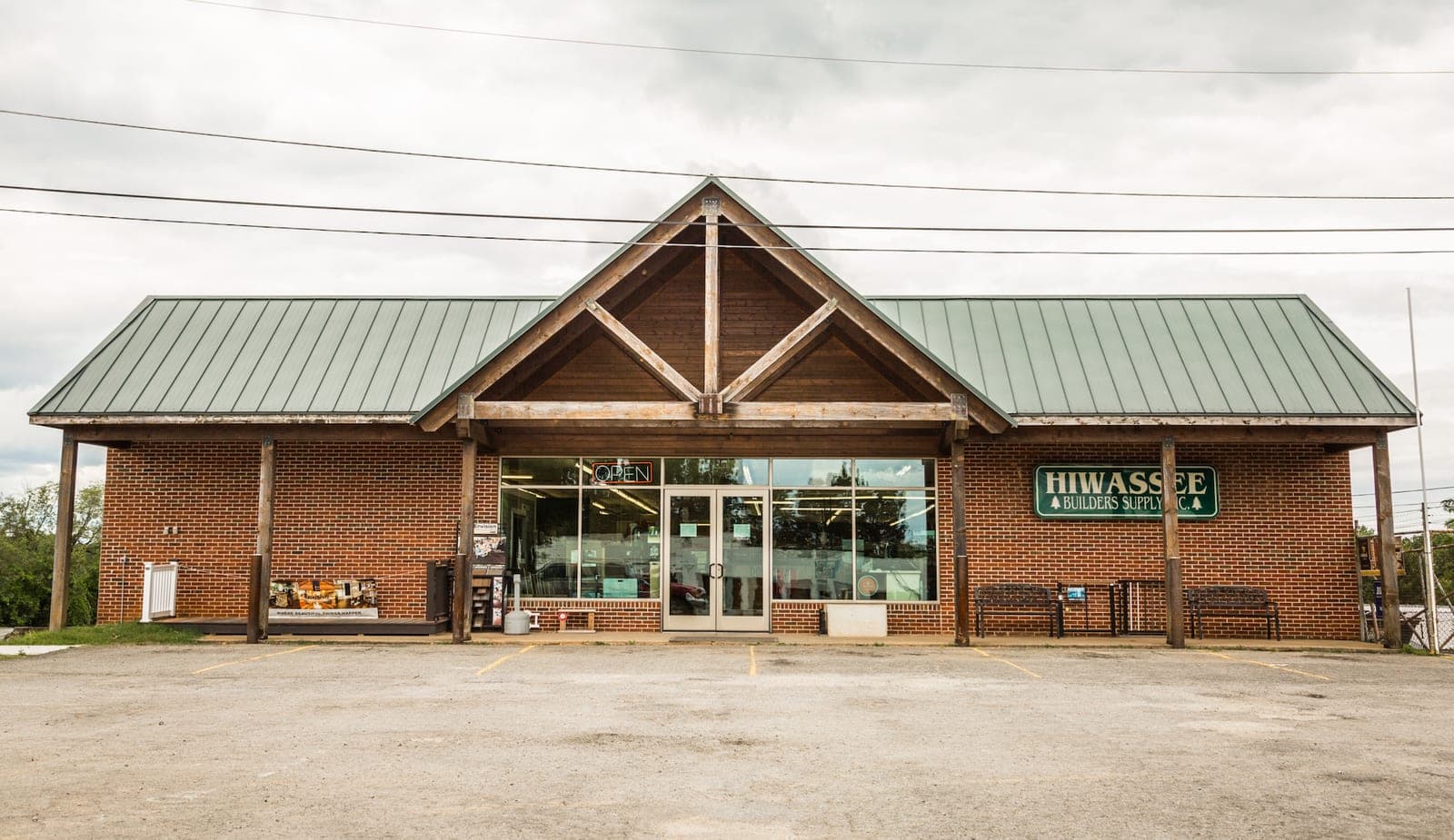 The Hiwassee Builders Supply storefront in Athens, Tennessee: a brick building with a green metal roof and timber entrance porch