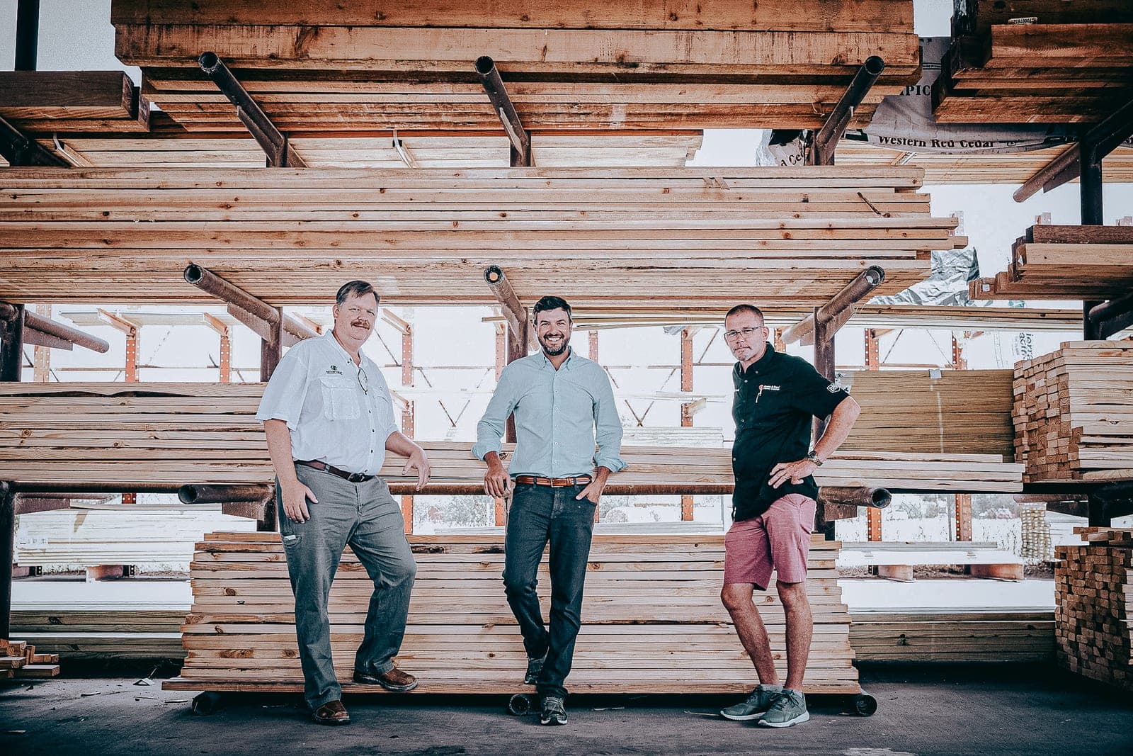 Three Nation's Best team members standing in front of racked dimensional lumber at one of their yards
