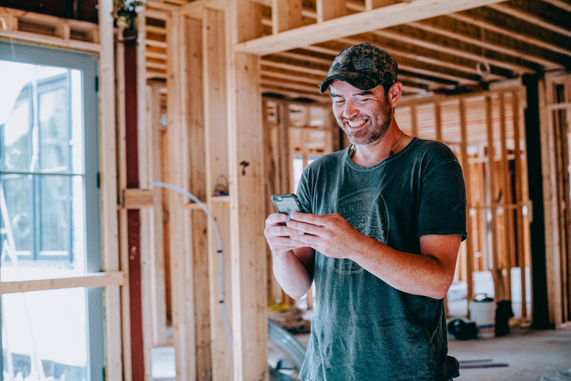A builder checking his phone inside a house under construction