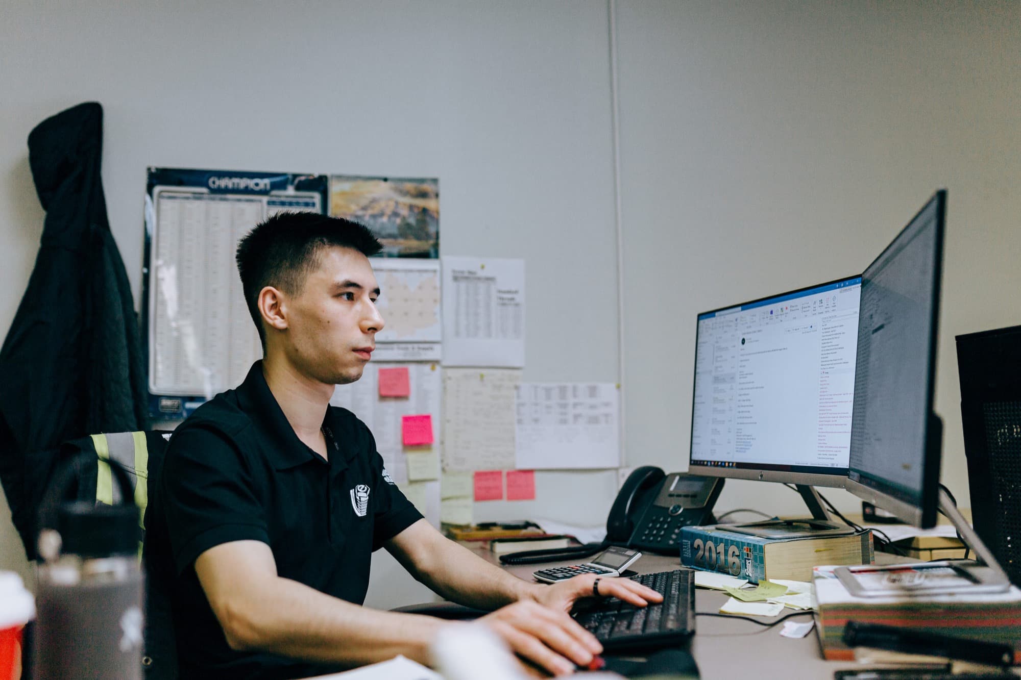 A dealer's back-office desk: one person working at dual monitors beside a desk phone