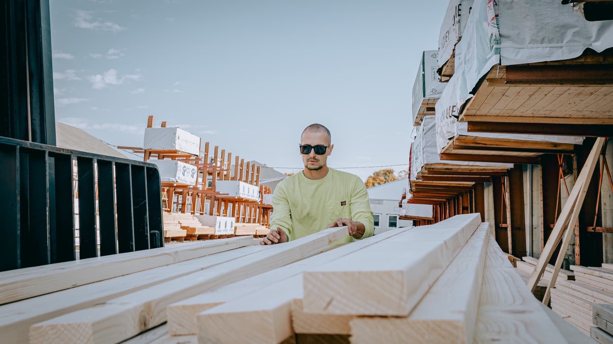 A yard worker loading dimensional lumber at a building supply yard